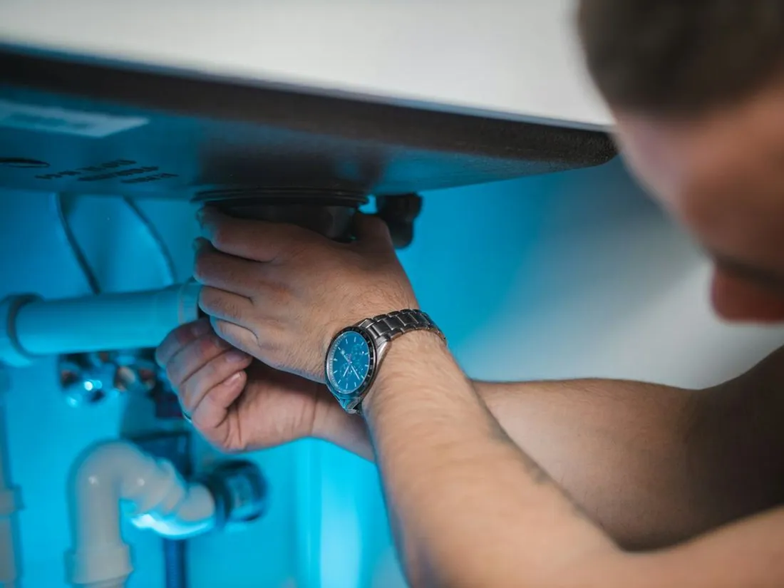 Plumber repairing pipes under a sink