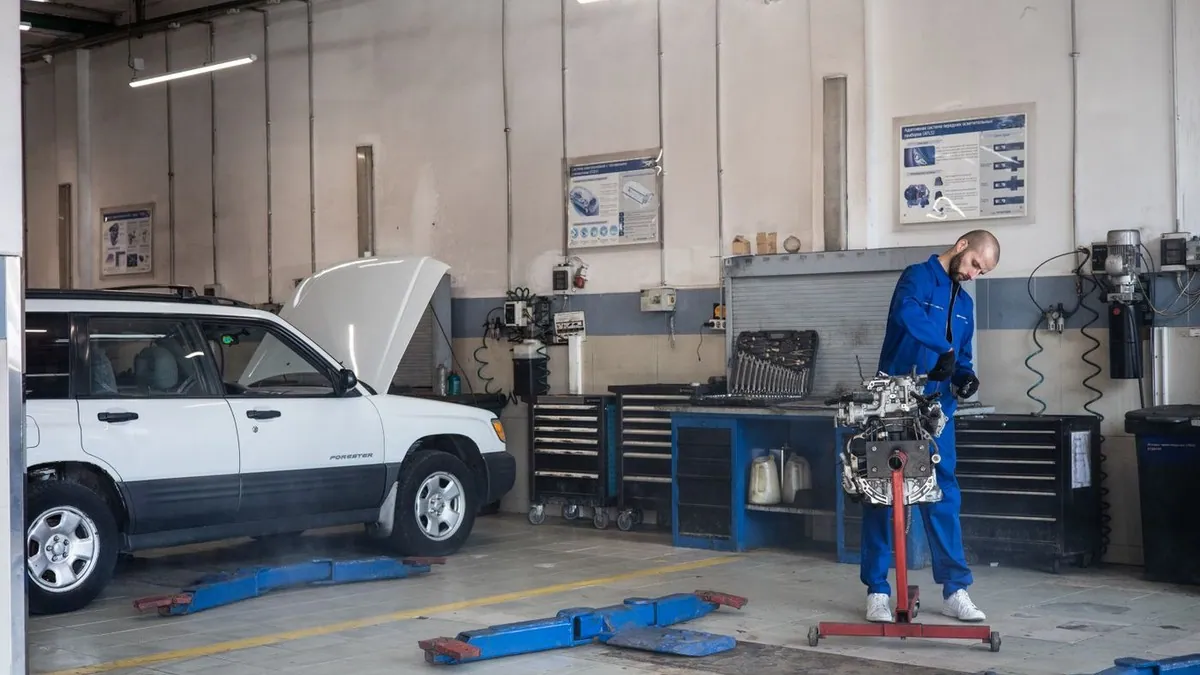 Mechanic in blue coveralls repairing an engine in an auto workshop