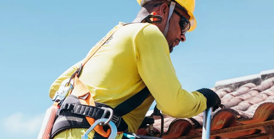 Roofer working on a tile roof under a blue sky