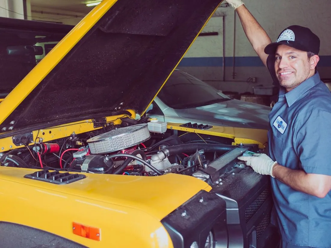 Mechanic with the hood open working on a car engine