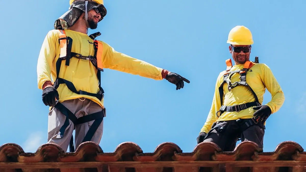 Two roofers discussing work on a residential rooftop