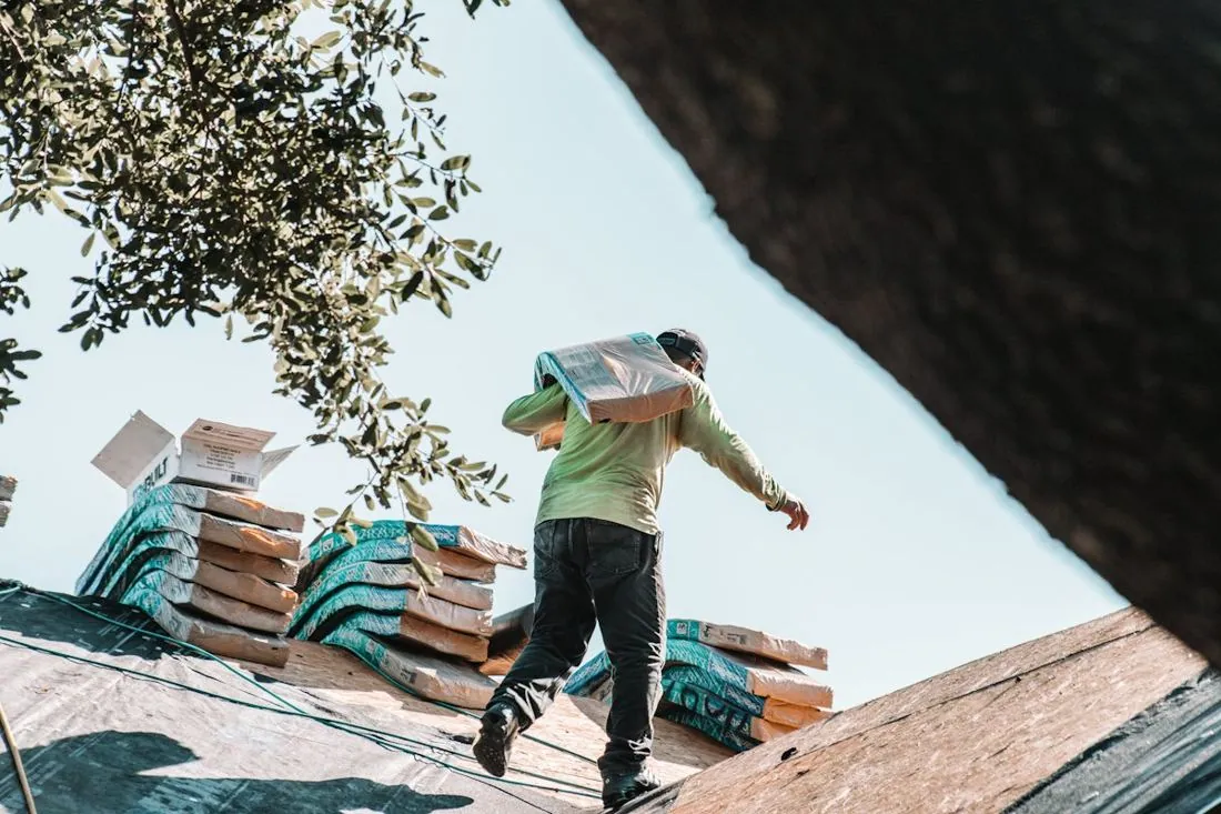 Roofer carrying shingles across a roof