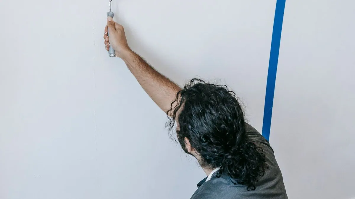 Painter using a roller to paint a wall during a home renovation