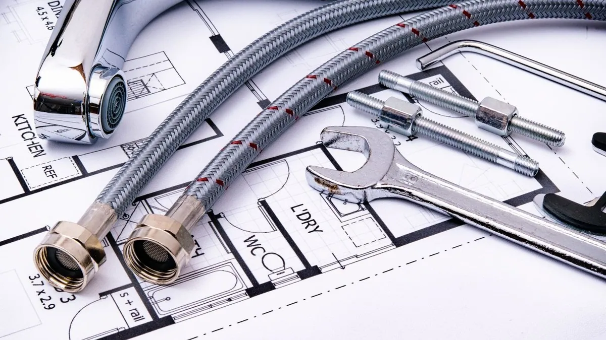 Plumbing fittings and a wrench laid out on a home floor plan
