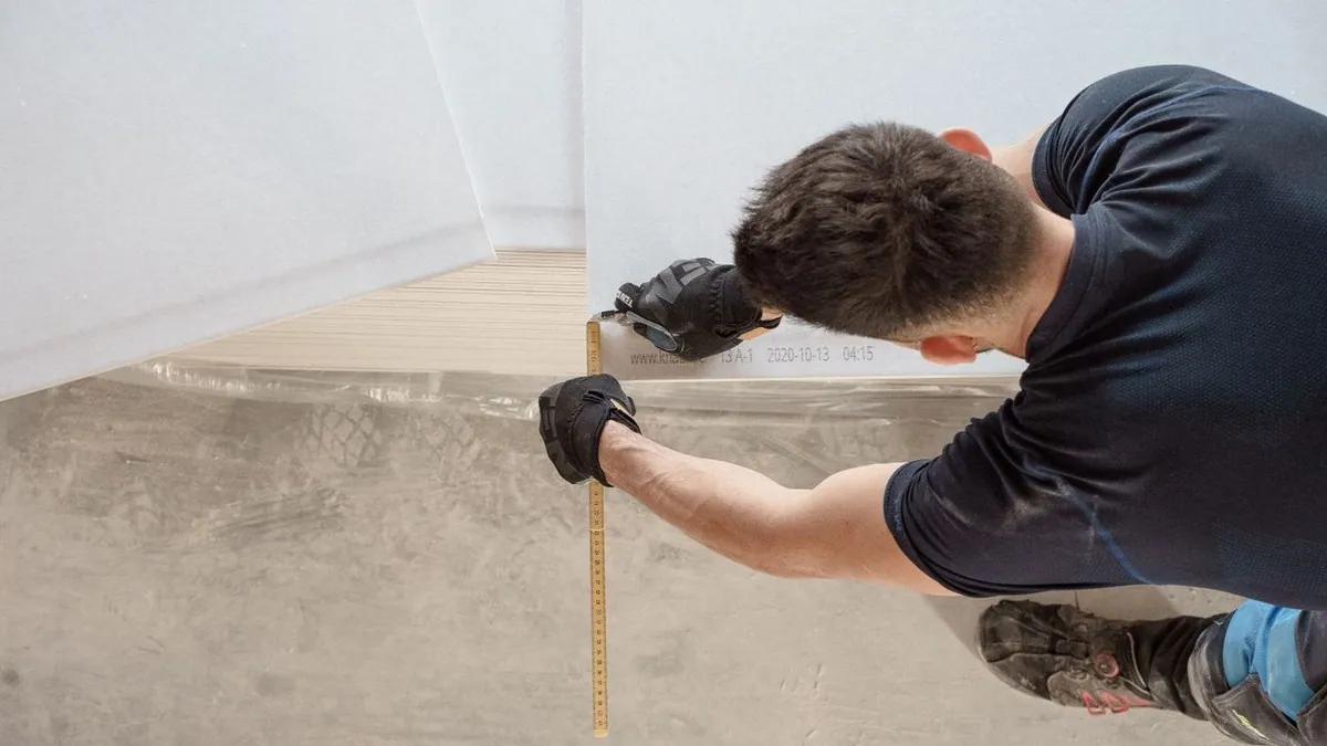 Worker measuring a flooring panel during a home renovation
